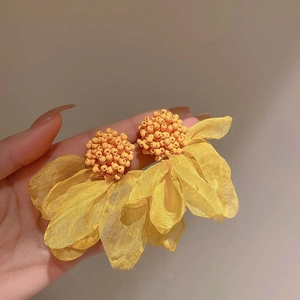 Close-up of handmade yellow tulle flower earrings with multi-layered petals and bead centers