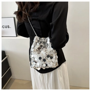 Close-up of silver sequin bucket bag with drawstring closure and fine chain strap