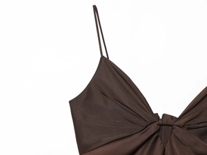 Détail de robe en satin marron foncé avec plis et fines bretelles sur fond blanc