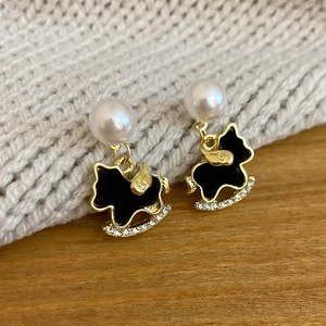 Detail of rocking horse earrings with black enamel, white pearl, and crystal accents