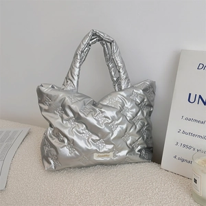 Detail of silver metallic quilted tote bag with bow stitching and soft padded texture