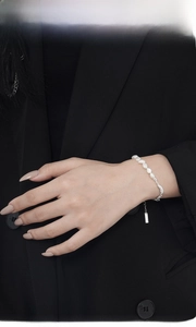 Detailed view of baroque pearls and silver irregular nuggets on a wrist with black suit
