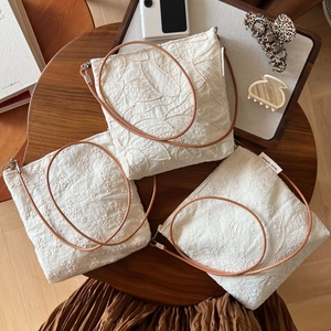 Detailed embroidery on cream cotton crossbody bags with brown leather straps