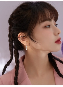 Detail shot of triple heart tassel earrings on a model showing the elegant drop length