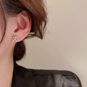 Close-up of elegant silver knotted stud earrings with sparkling cubic zirconia on model