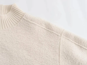 Detail of ribbed crew neck and soft wool texture on cream knitted sweater for women