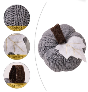 Detailed view of grey knitted pumpkin with fabric leaf and rustic lanyard for decor