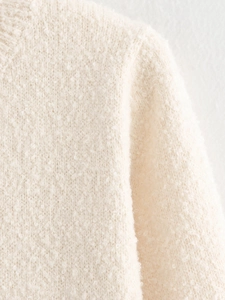 Close-up of beige chunky knit sweater texture on shoulder and sleeve seams