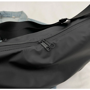 Detail of black nylon dumpling bag with double metal zippers and wide shoulder strap
