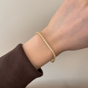 Detail of a gold tennis bracelet with 2mm round zircons worn on a wrist for a luxury look