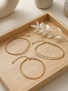 Close-up of double-layered gold snake chain and beaded link bracelet on wood tray