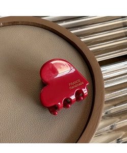 Detail view of a small red heart hair claw clip with France Handmade text on leather tray