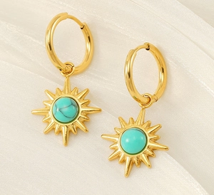 Detailed view of bohemian 18K gold starburst earrings with turquoise stone on white fabric