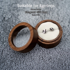 Detailed top view of a round black walnut jewelry box with a clear window and ear studs