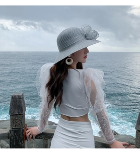 Close-up of white bubble sleeves with polka dot mesh texture and wide-brim sun hat detail