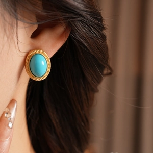 Close-up of vintage oval turquoise gemstone earring with twisted gold metal border