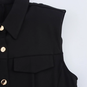 Detail of black sleeveless dress featuring shoulder pads and gold metal button accents