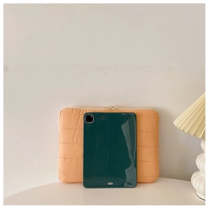 Minimalist orange quilted laptop sleeve shown next to a tablet for size reference