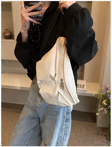 Detail of off-white faux leather crossbody bag with multiple silver zippers on model