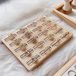 Solid walnut wood ring display tray with multiple gold rings on white faux fur background