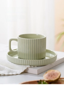 Detail of mint green ceramic coffee cup and saucer with elegant vertical stripe texture