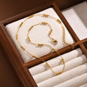 Detailed close-up of golden beaded chain with lobster clasp on velvet jewelry tray