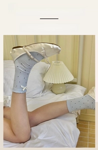 Detail of light blue polka dot socks with white bows and elastic wavy cuffs