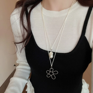 Close-up of double-layer necklace with baroque pearl and silver hollow flower pendant