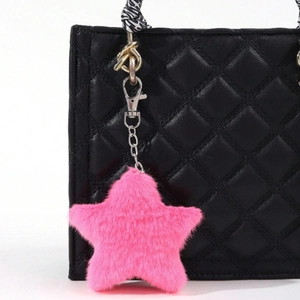 Close-up of a fluffy pink star-shaped plush pendant attached to a quilted black bag