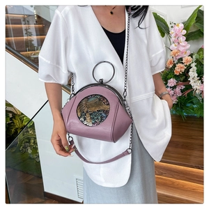 Close-up of purple shell bag featuring intricate elephant relief and metal ring handle