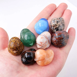 Variety of small polished natural crystal duck carvings in different colors held in hand