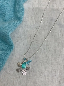 Detail der silbernen Blumenkette mit grünem Katzenauge-Anhänger und blauen Perlen