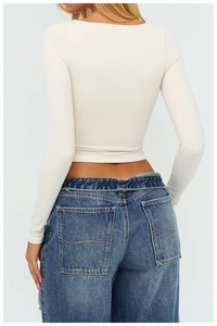 Vista posteriore di un top corto beige a maniche lunghe e jeans in denim blu