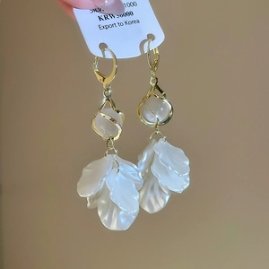 Detailed macro view of gold-plated petal earrings with elegant pearls and silver hooks