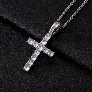 Cross pendant necklace with sparkling cubic zirconia on a black textured background