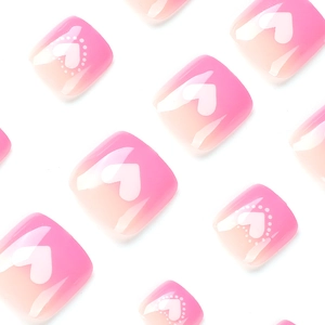 Faux ongles d'orteils dégradés roses avec motifs de cœurs blancs et fini brillant