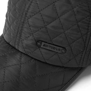 Close-up of quilted winter baseball cap with metal logo plate and premium leather piping