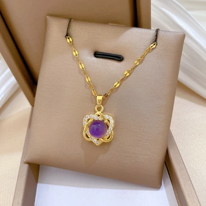 Macro shot of titanium gold necklace with purple gemstone and heart-shaped diamond pavé detail