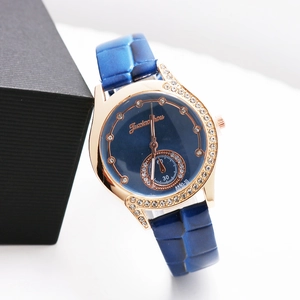 Macro detail of blue leather strap and rose gold rhinestone-studded watch bezel
