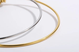 Makro-Detail von polierten Gold- und Silberarmbändern im minimalistischen Herz-Design