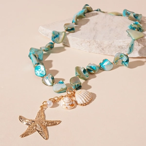 Detail of beaded shell necklace featuring golden starfish, white pearl and teal sea glass