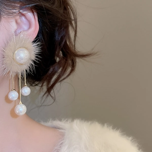 Detail of elegant pearl tassel earring with cream fur ball shown on ear
