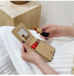 Detail of cream mini lipstick bag with vertical stripes, inner mirror and magnetic flap