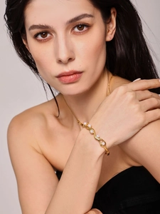 Detail of 18K gold-plated C-shaped bangle with organic waves and white pearls