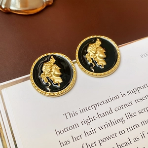 Vue macro de boucles d'oreilles camée vintage dorées posées sur un livre d'art