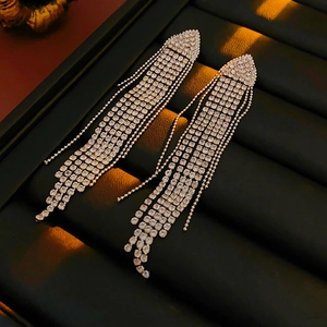 Close-up of silver tassel earrings with sparkling rhinestones on a black jewelry box