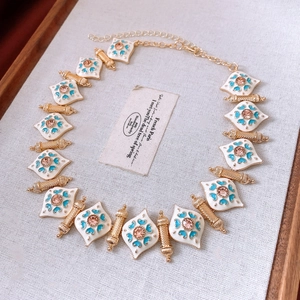 Detailed macro view of French vintage necklace with white enamel and golden plating
