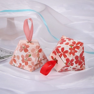 Detail of pyramid-shaped wedding candy boxes with cherry blossom patterns and ribbons
