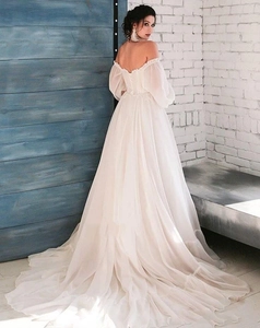 Detail of elegant ivory wedding dress showing puff sleeves and a flowing mesh train