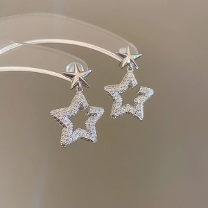 Macro detail of silver star earrings with pave set cubic zirconia on a display stand